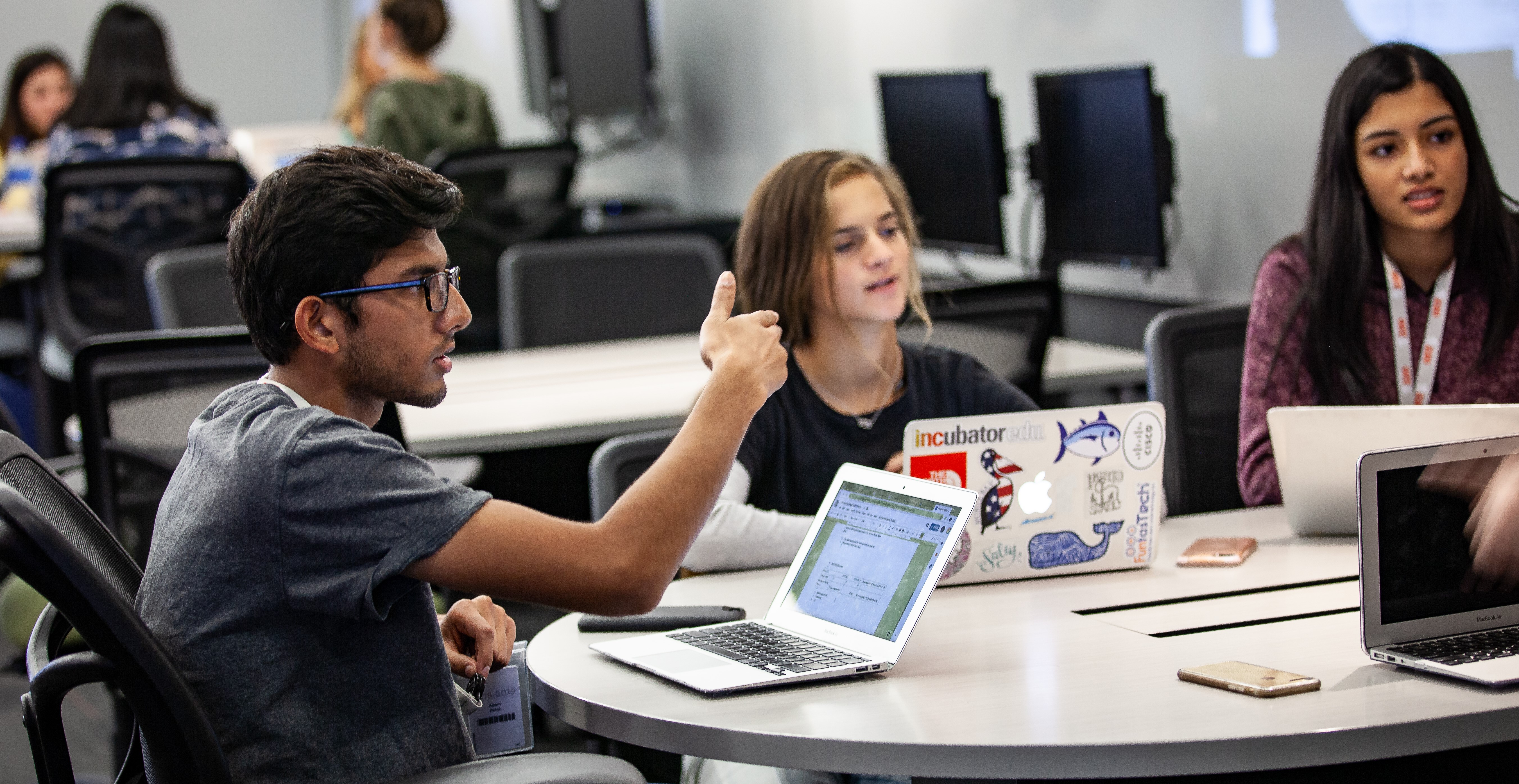 students with laptops talking in group